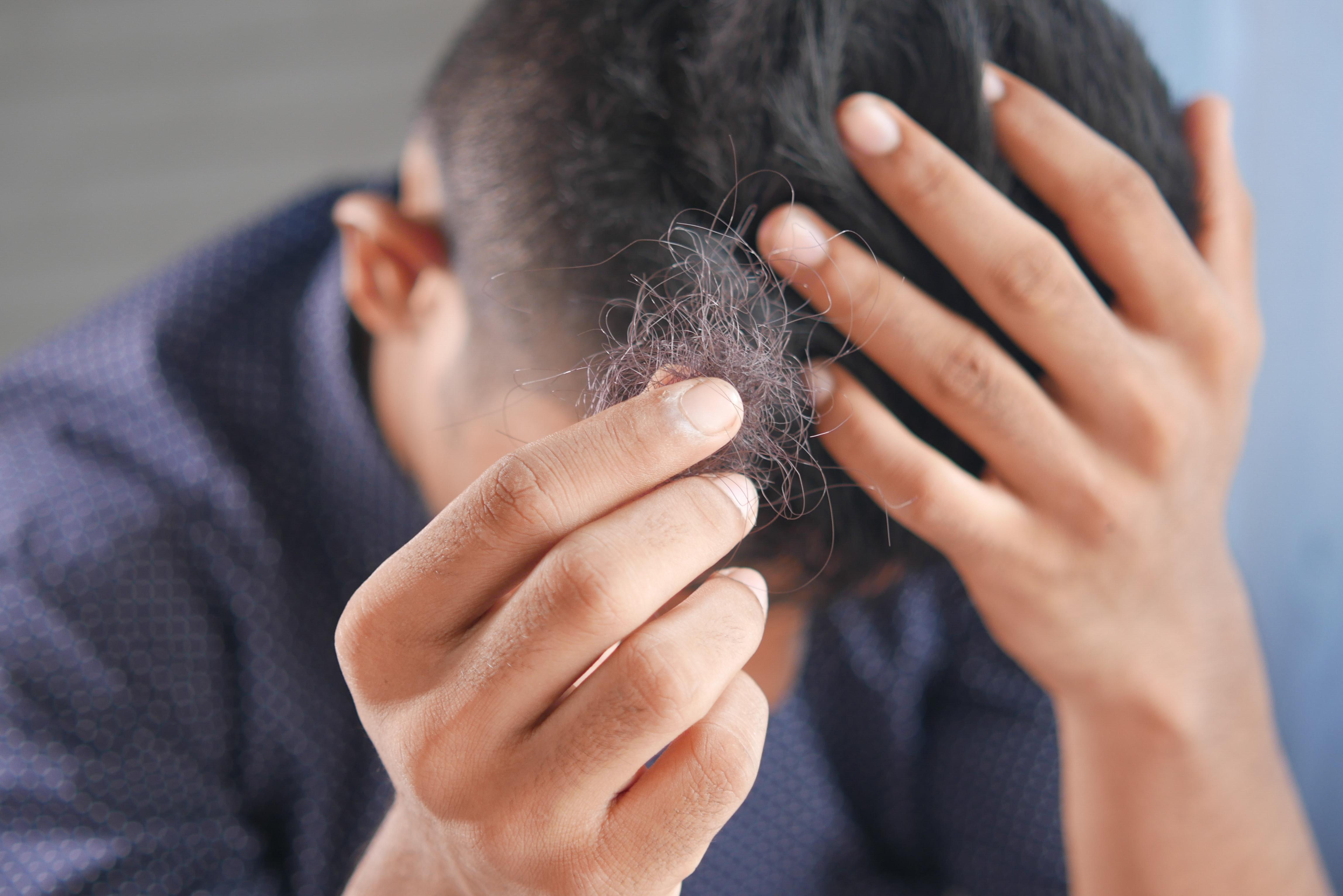 Person holding a tuft of their hair