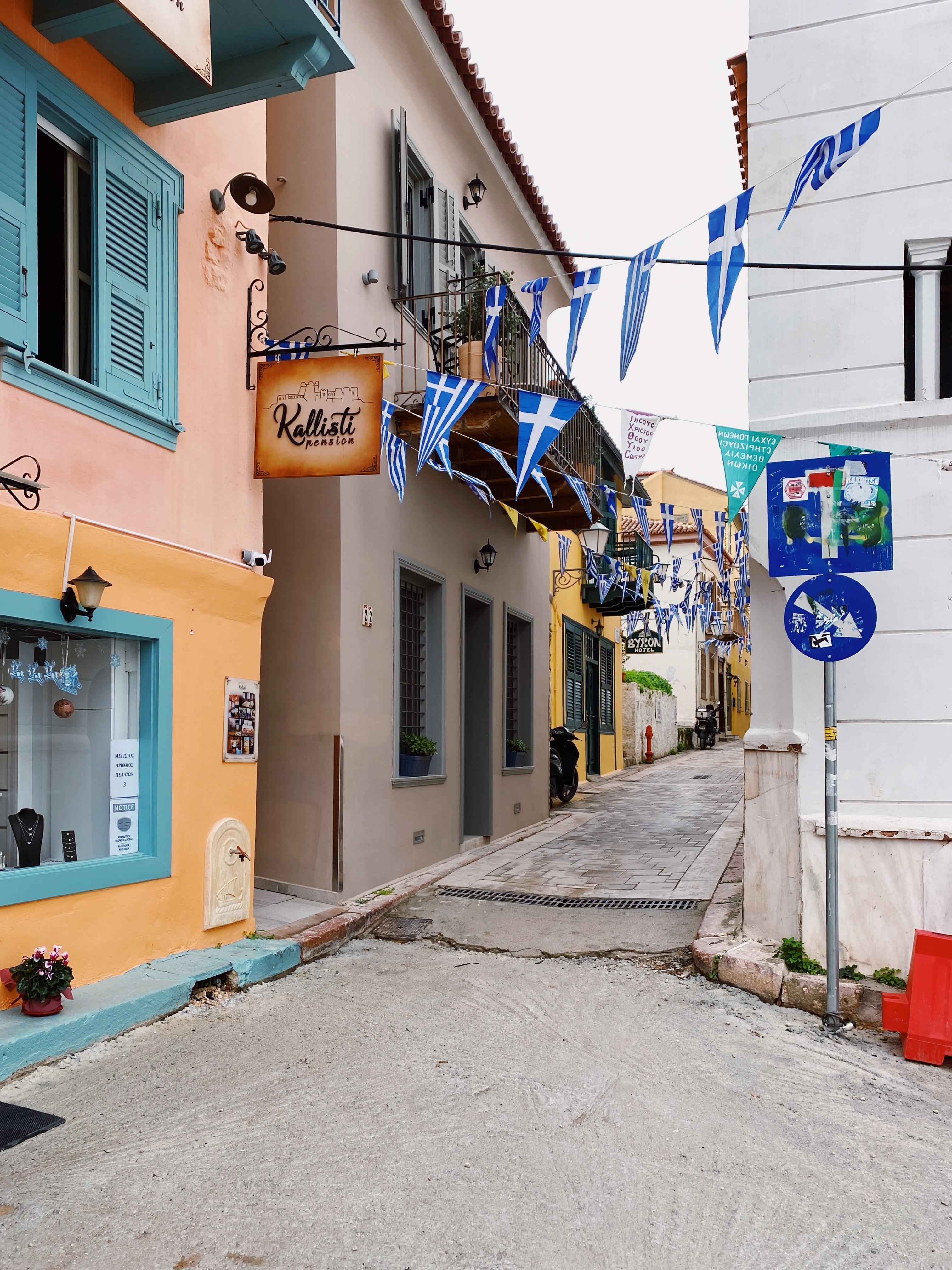 photo of a street in Greece with Greek flags hung between two buildings