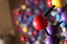 A physical model of DNA molecules against a colorful background.
