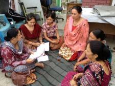 Six women (members of Women's Rehabilitation Center in Nepal) are gathered in a circle, intently listening and discussing.