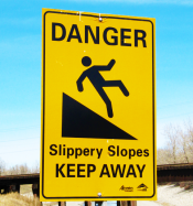 Yellow warning sign stating, "Danger Slipper Slope--keep away." A figure is featured slipping from an incline.