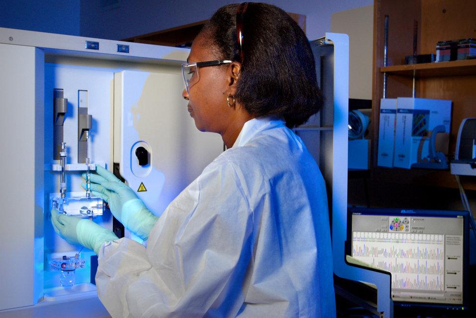 Woman in lab coat looking at test tubes