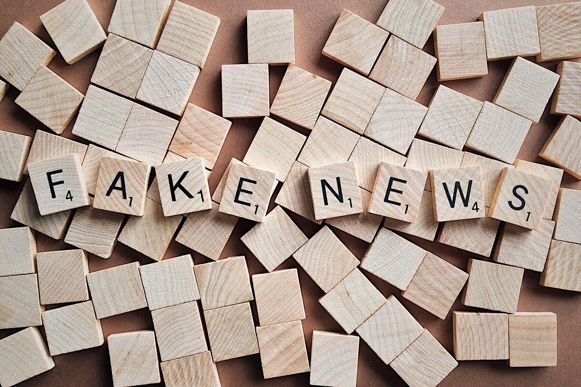 Wooden scrabble game pieces that spell out "fake news"