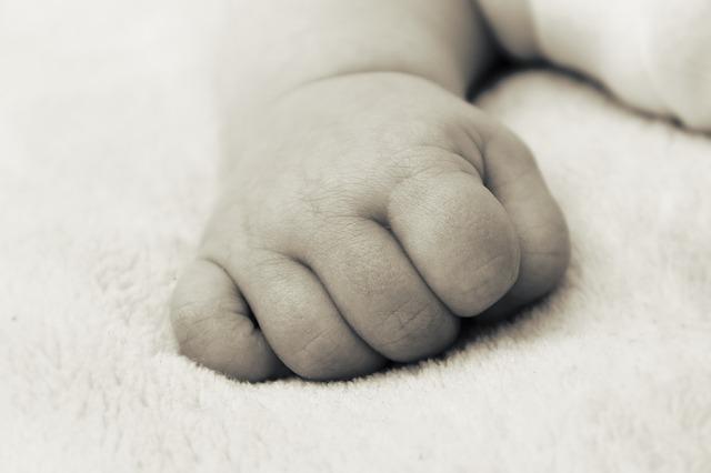 Grayscale image of a baby's fist, resting as they lay down.