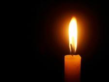 A candle, against a dark background, burns at the corner of the image.