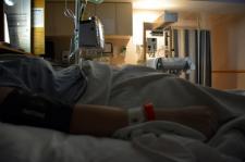 Patient is in a dimly lit room, laying on a hospital bed.