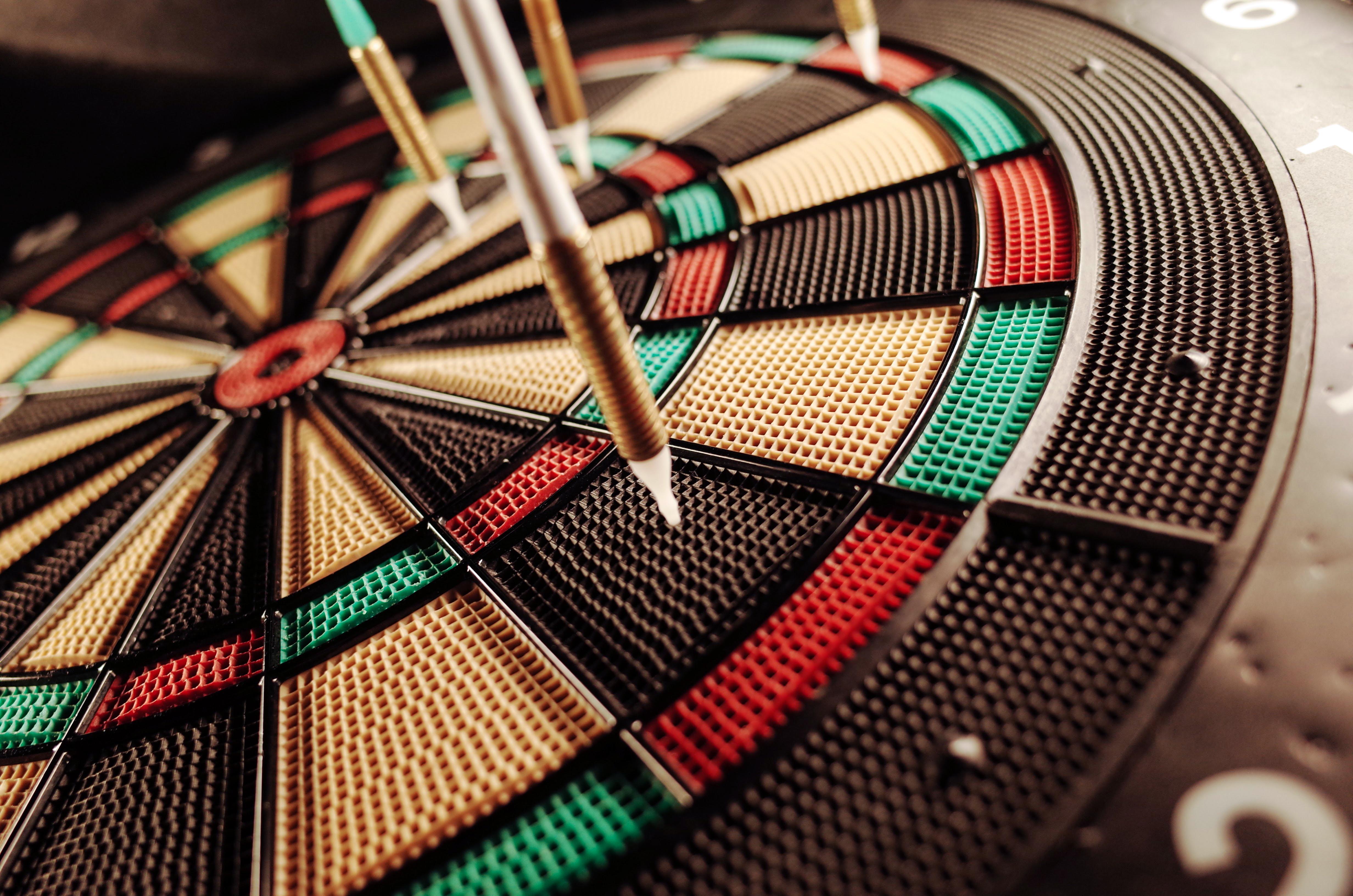 Several darts miss the target on a dart board.