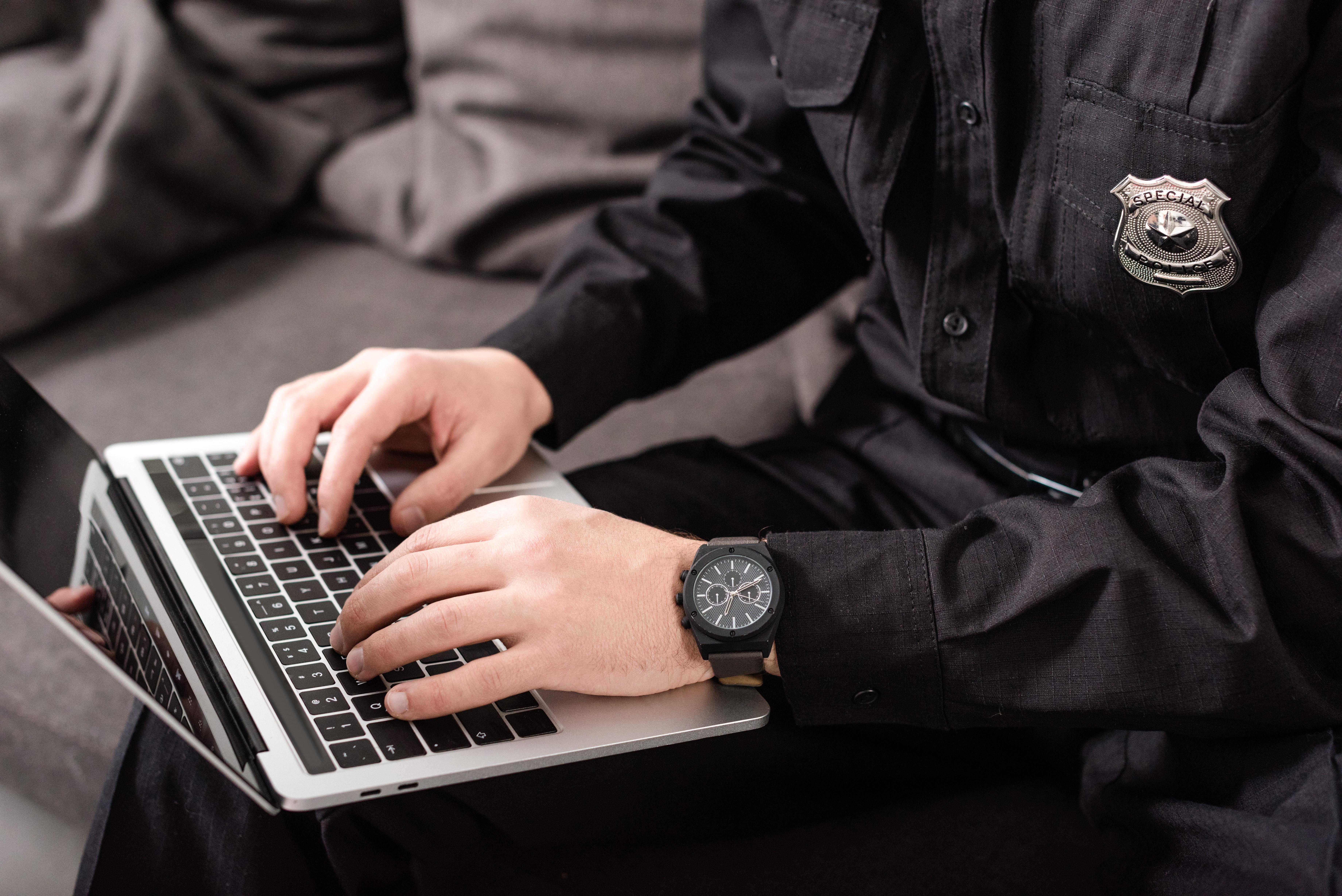 a uniformed police officer searches on laptop