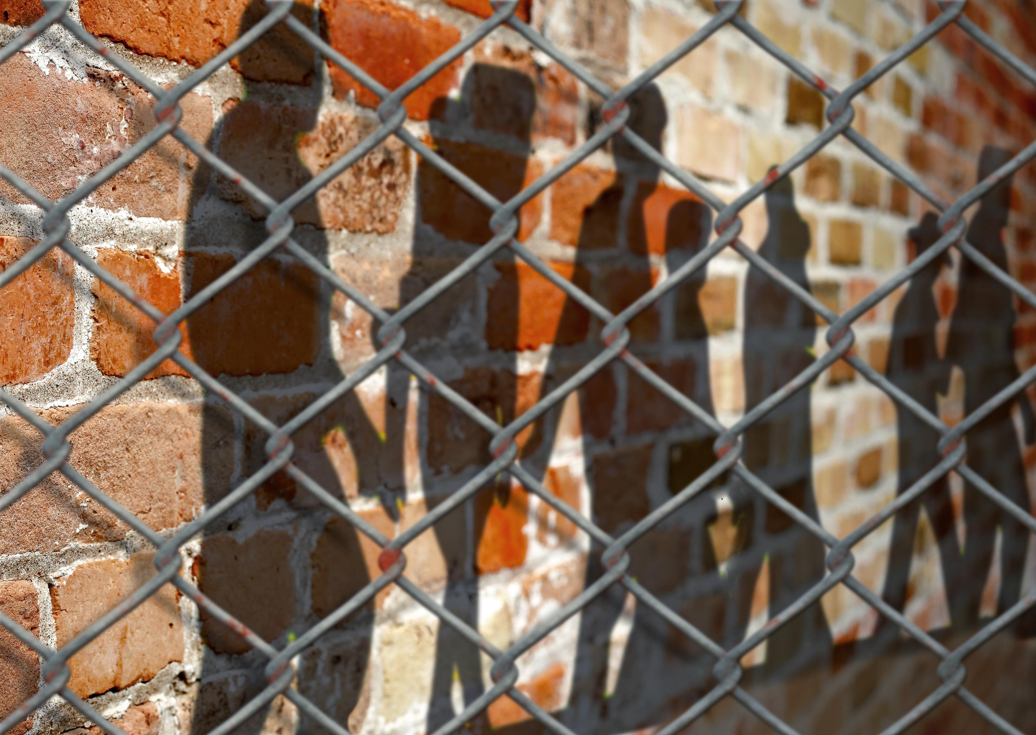 Silhouettes of prisoners behind a fence. 