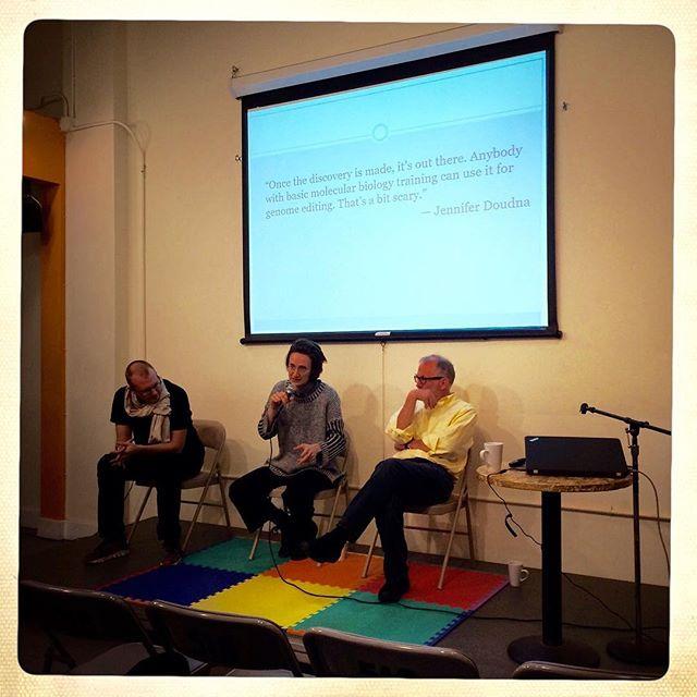 Shaping SF Panel presenters Tito Jankowski, Elliot Hosman, and Pete Shank look thoughyfully engaged in discussion. Above them is a quote from Jennifer Doudna stating, "Once the discovery is made, it's out there. Anybody with basic molecular biology training can use it for genome editing. That's a bit scary."