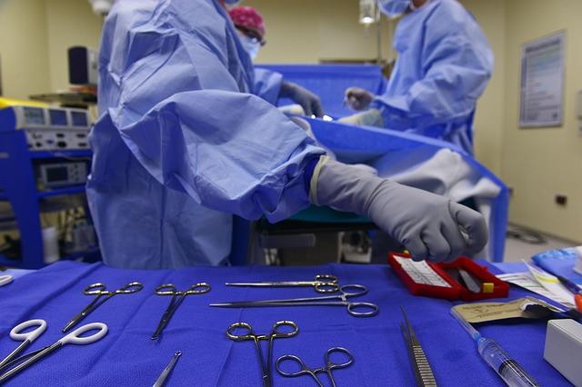 A surgeon's assistant handles surgery tools on a stand in the operating room.