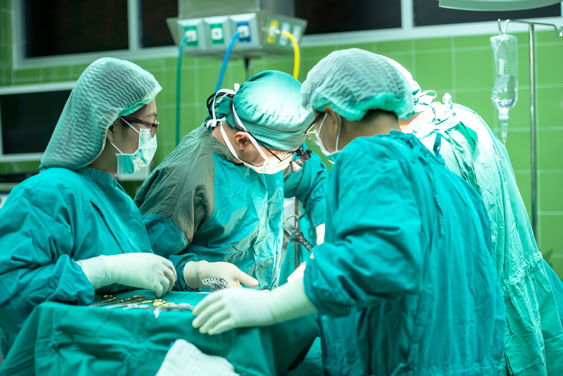 A team of surgeons are performs surgery. The patient is not visible.