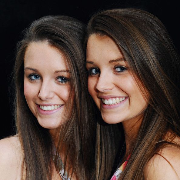 Two twin girls with brown hair standing next to each other