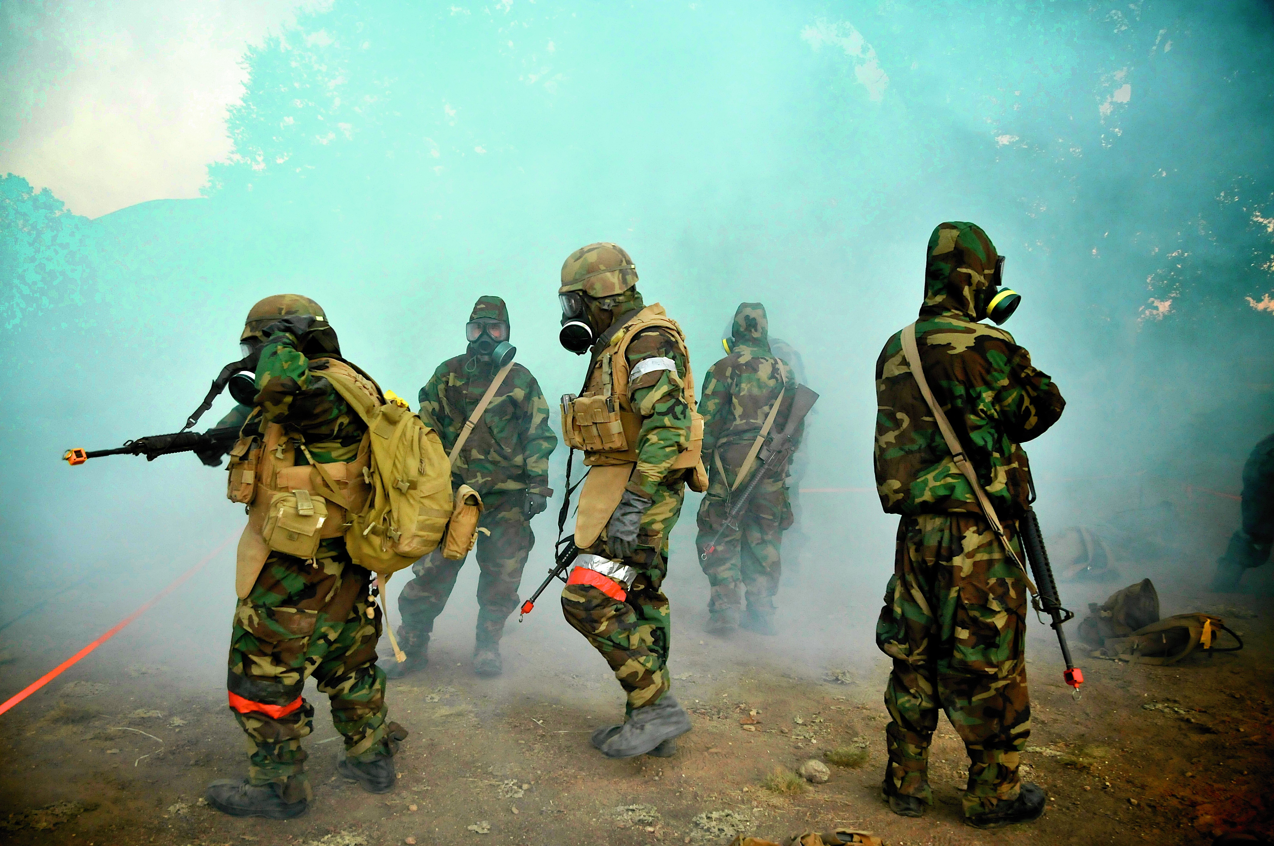 Five soldiers are dressed in protective gear, seeming to scout the area of land. The air appears thick and musty.