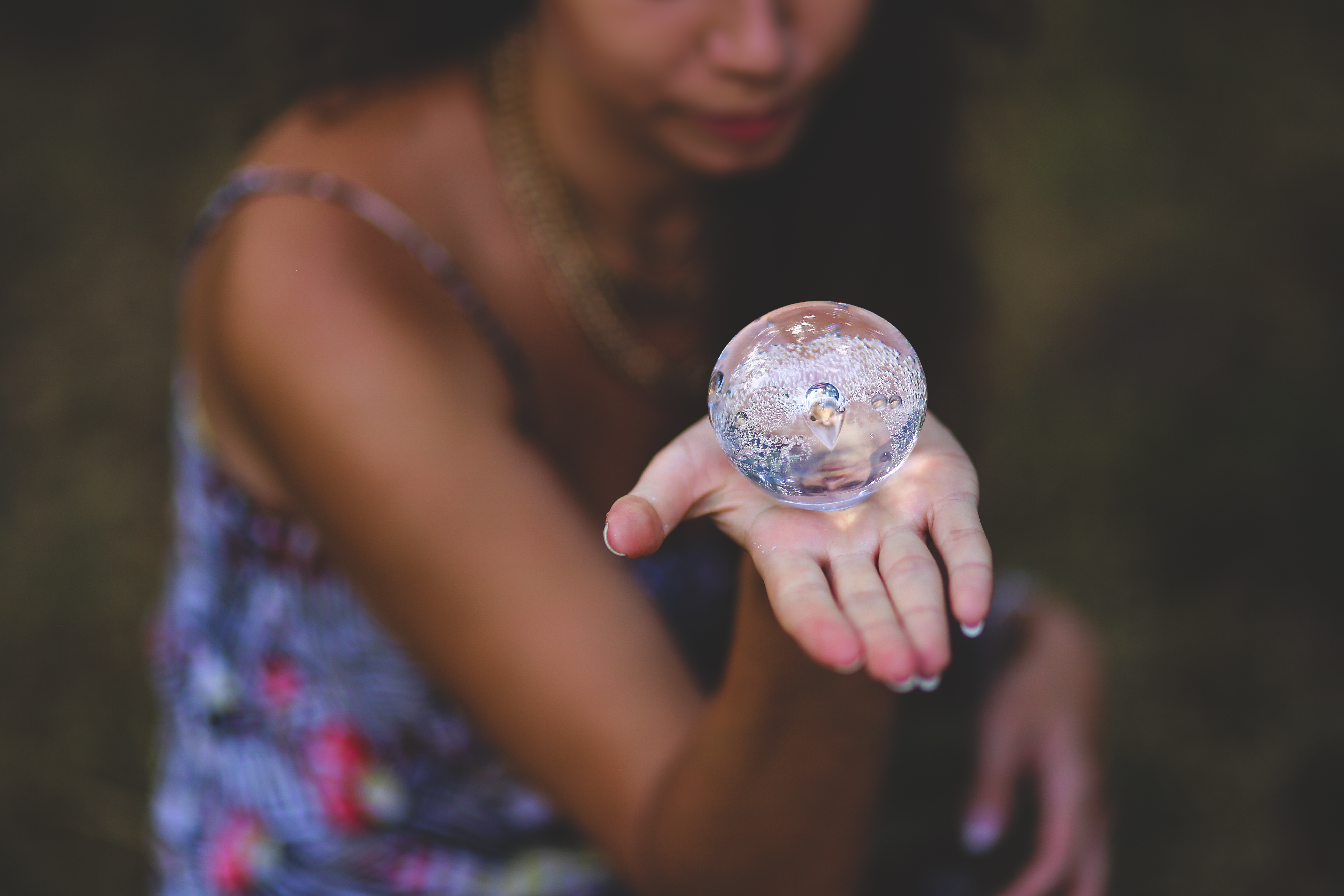 A woman of color holds a circular glass object in her opened left palm.