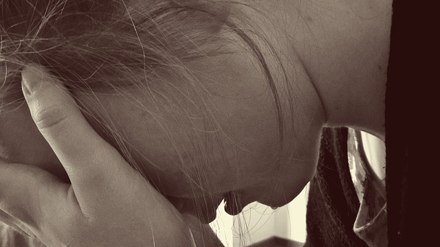 A person leans and covers their head, expressing sadness.